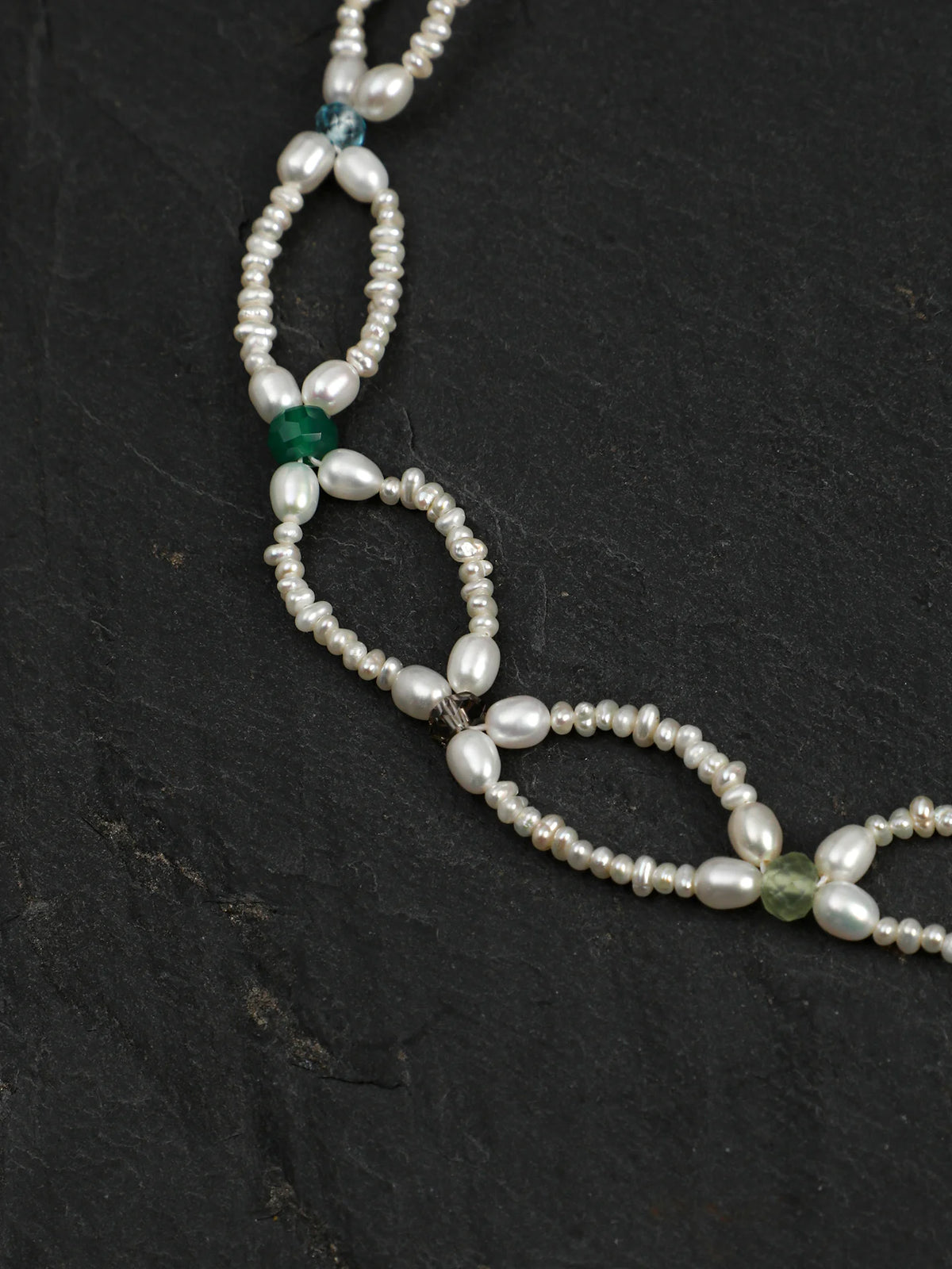 Close-up of the woven pearl lace and colored gemstone accents