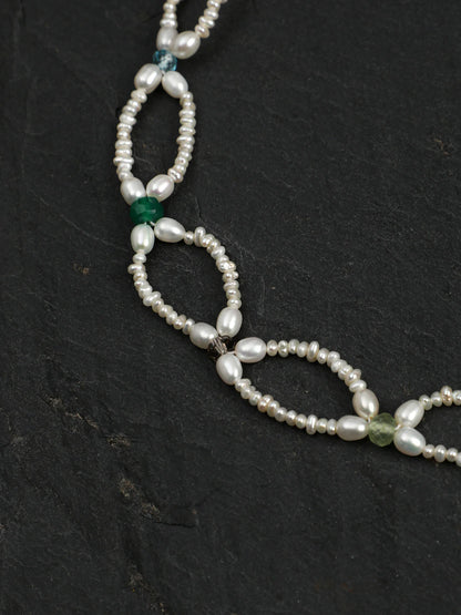 Close-up of the woven pearl lace and colored gemstone accents
