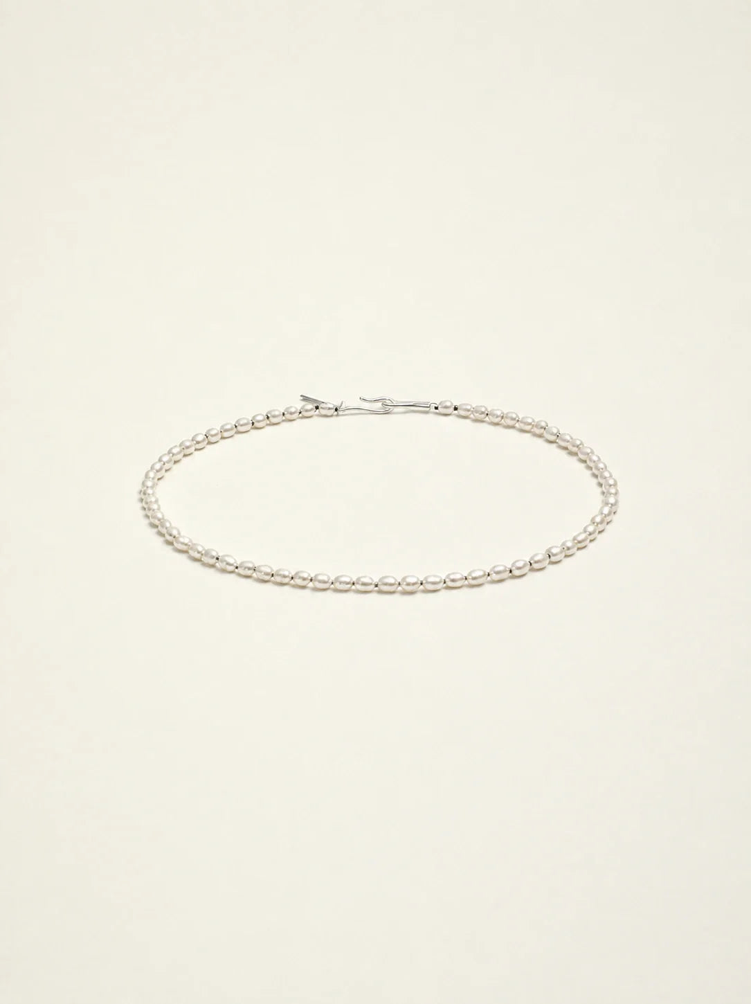 Natural freshwater seed pearl choker necklace on warm ivory background