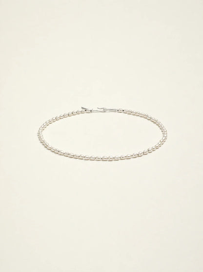 Natural freshwater seed pearl choker necklace on warm ivory background