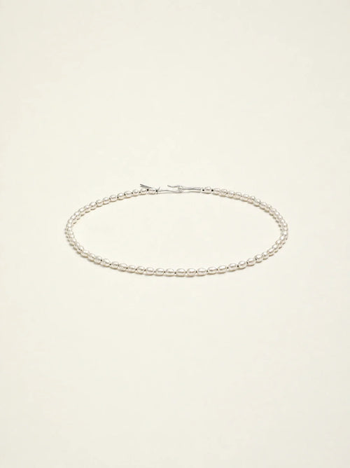 Natural freshwater seed pearl choker necklace on warm ivory background
