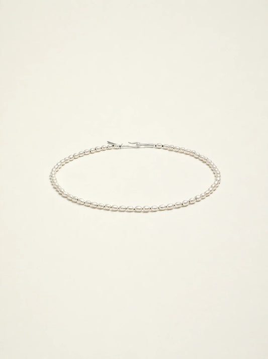 Natural freshwater seed pearl choker necklace on warm ivory background